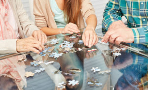 Family and seniors play a puzzle as dementia prevention in retirement home